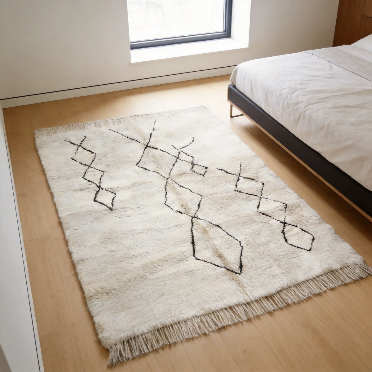 Moroccan wool rug, three offset chains of black diamonds on a cream wool ground in a bedroom setting