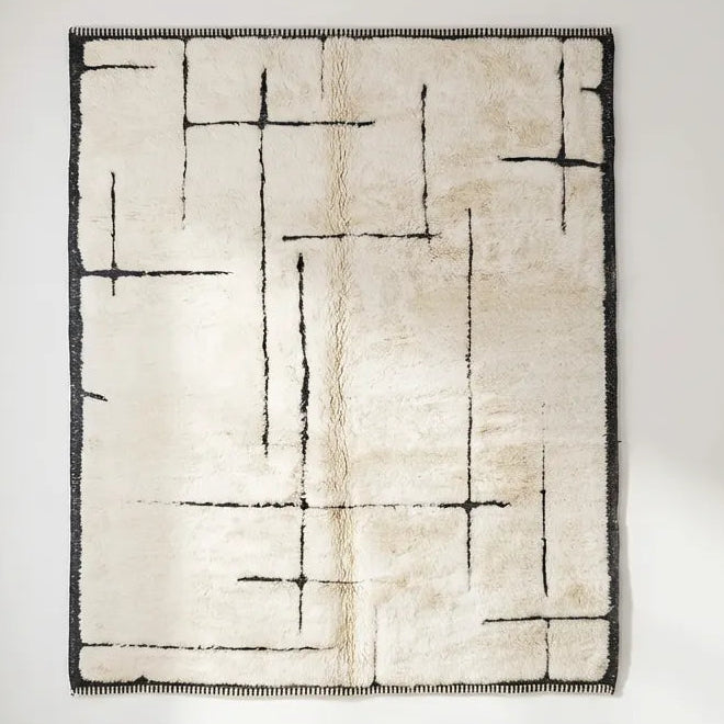 Front view of Beni Ourain wool rug, asymmetrical black geometric lines and a dark border on a light ground