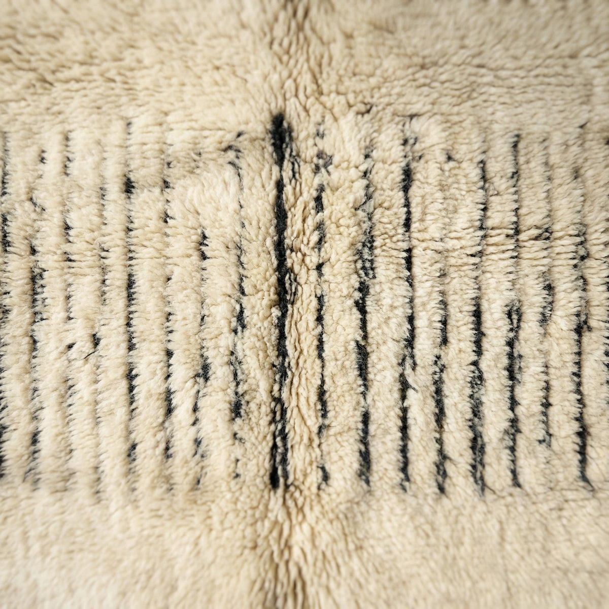 Moroccan wool rug, short dark blue lines near one end of a cream high-pile ground, product view 2