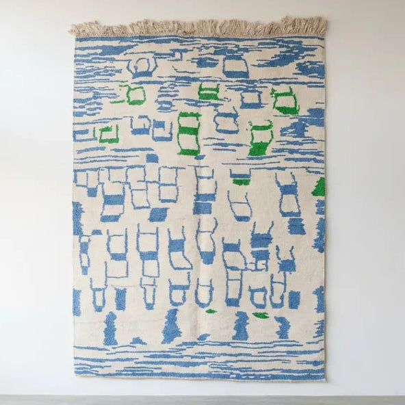 Front view of Moroccan wool rug, bright blue graphic shapes and green accents on a cream ground