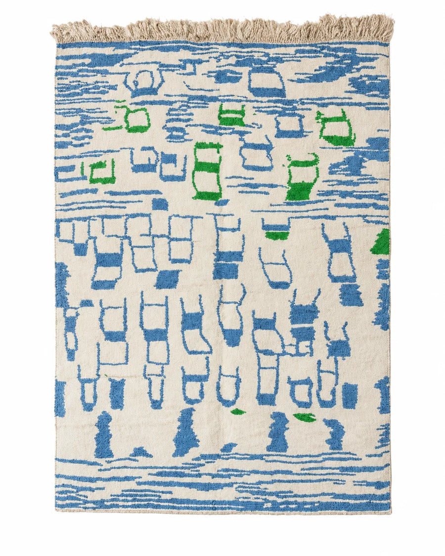 Front view of Moroccan wool rug, bright blue graphic shapes and green accents on a cream ground