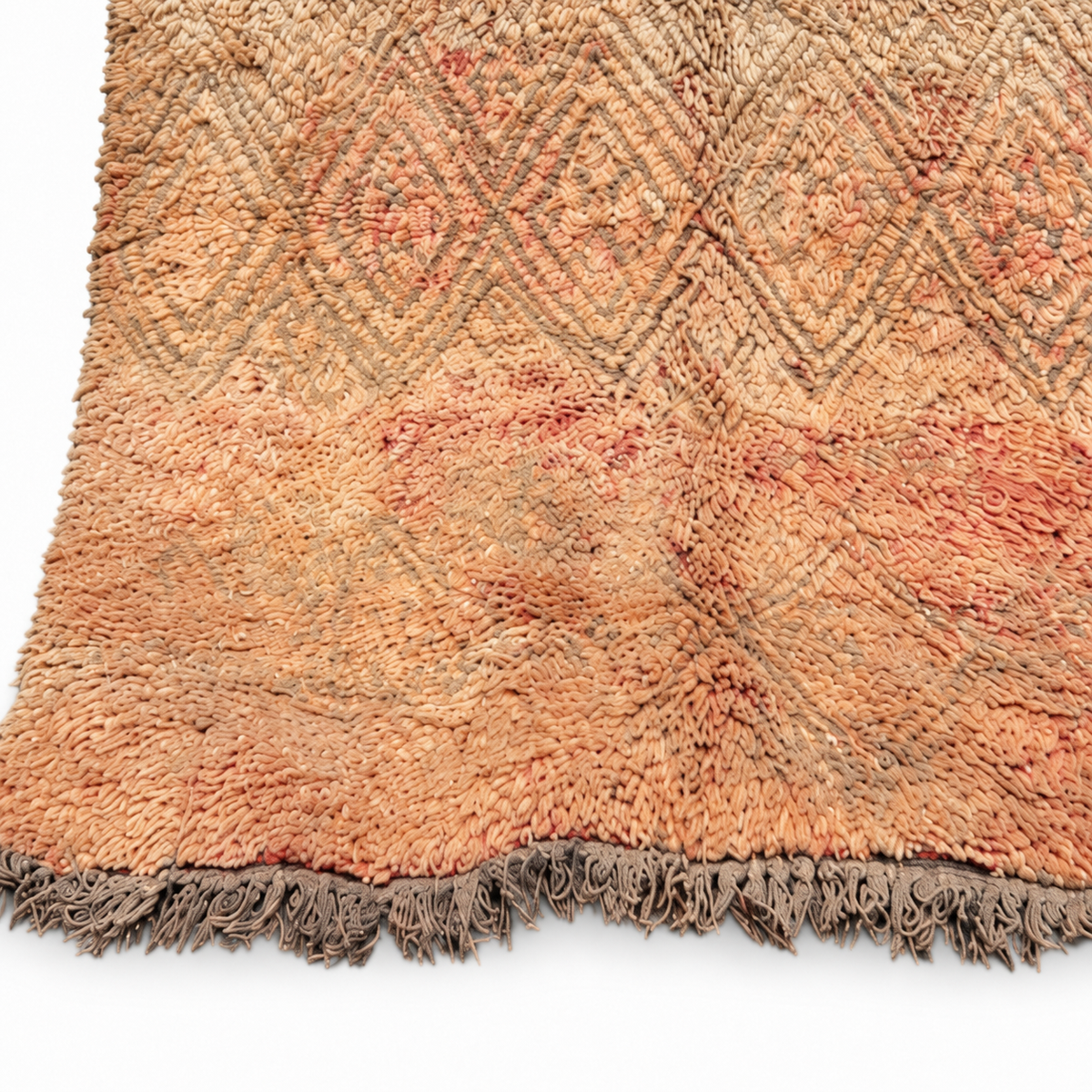 Edge and dark fringe of the beige vintage Moroccan rug with peach accents.